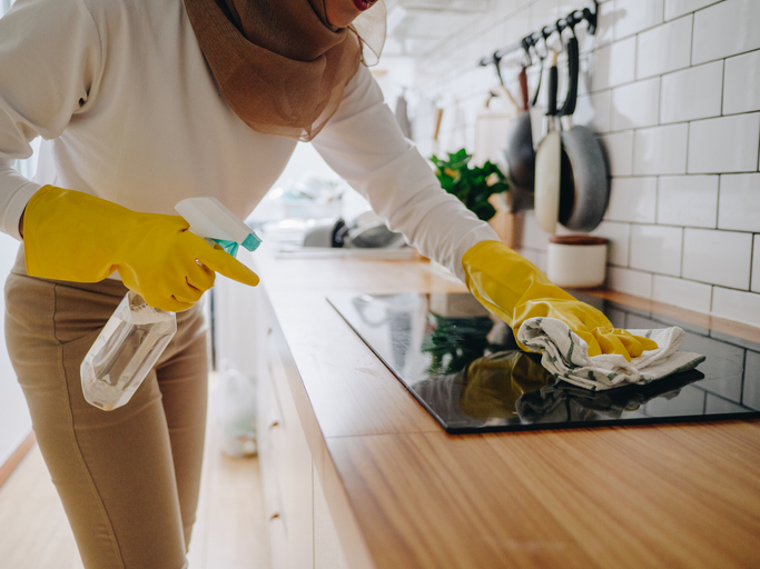Professionelle Küchenreinigung Freising: Fachkraft der Schlueter Group reinigt Ceranfeld hygienisch sauber.