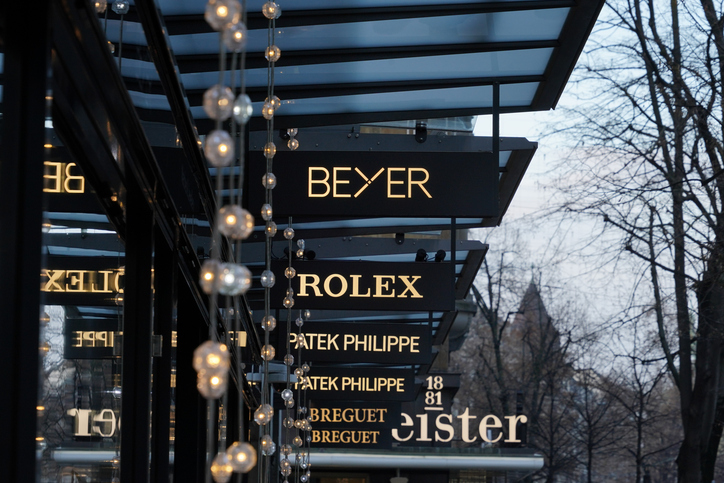 Eine makellos saubere Fassade eines Luxusgeschäfts in München mit Leuchtreklamen von Rolex und Patek Philippe, Symbol für die exklusive Einzelhandels- & Showroomreinigung der Schlueter Group.