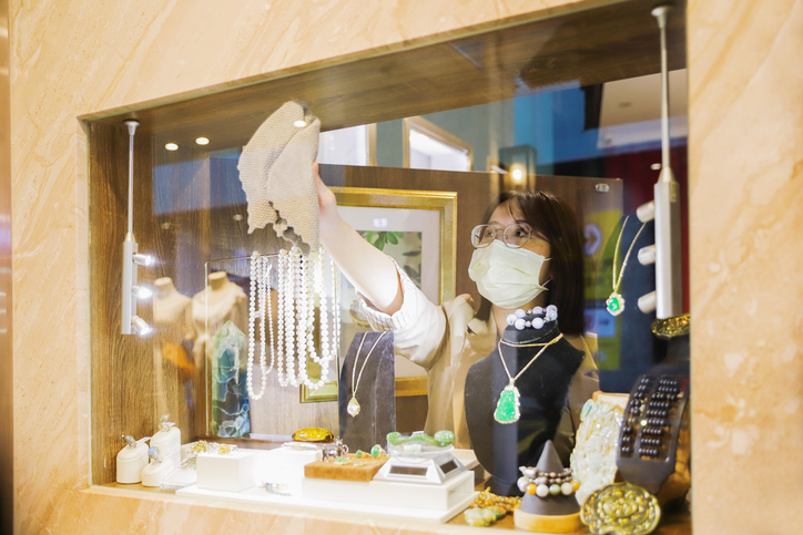Professionelle Reinigungskraft reinigt sorgfältig eine Schmuckvitrine in einem Münchner Luxusgeschäft, um den Wert der exklusiven Ware zu schützen und das Markenimage zu stärken.