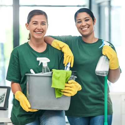 Professionelles Reinigungsteam für Büros und Praxen in München Zwei freundliche Reinigungskräfte der Schlueter Group für professionelle Gebäudereinigung in einem Büro in München.