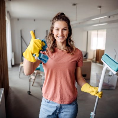 Reinigungskraft bei der Arbeit – Ihre beste Wahl für Sauberkeit Freundliche Reinigungskraft mit Daumen hoch und Reinigungsutensilien – beste Reinigungsfirma in Aktion.